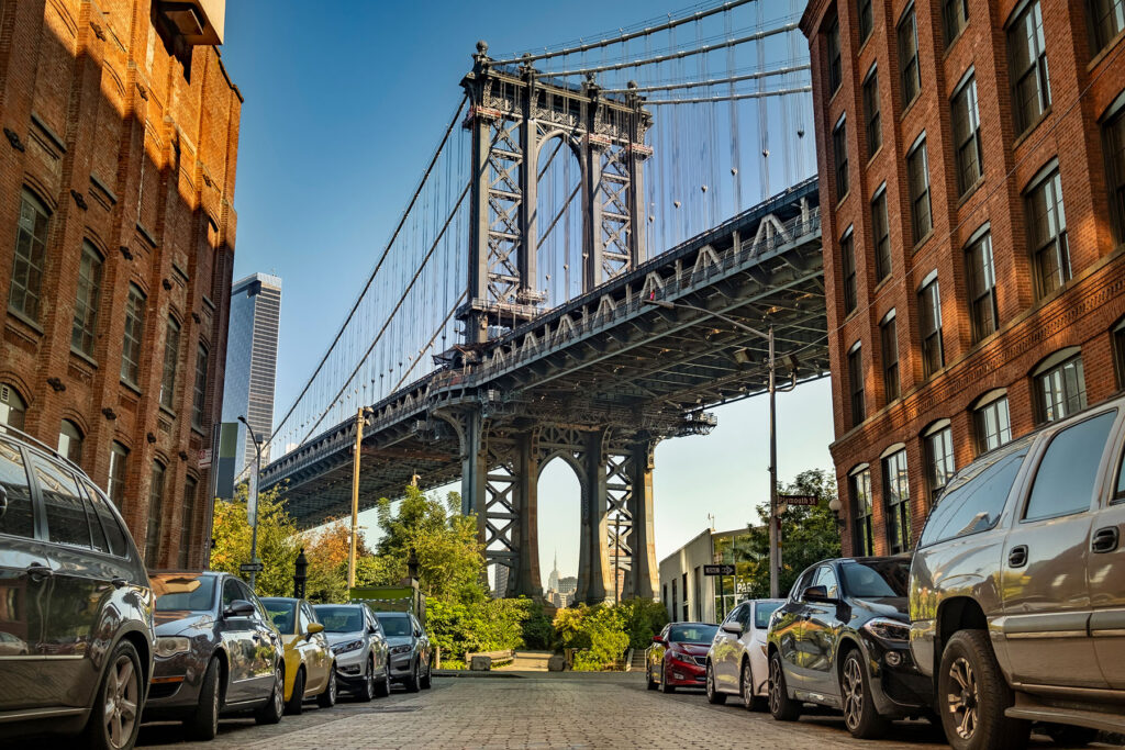 Manhattan Bridge viewed from a cobblestone street between brick buildings in Brooklyn
