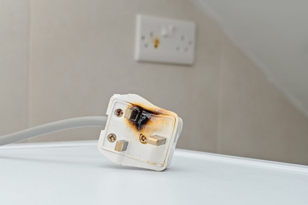 Burned AC power plug sitting in front of power outlet