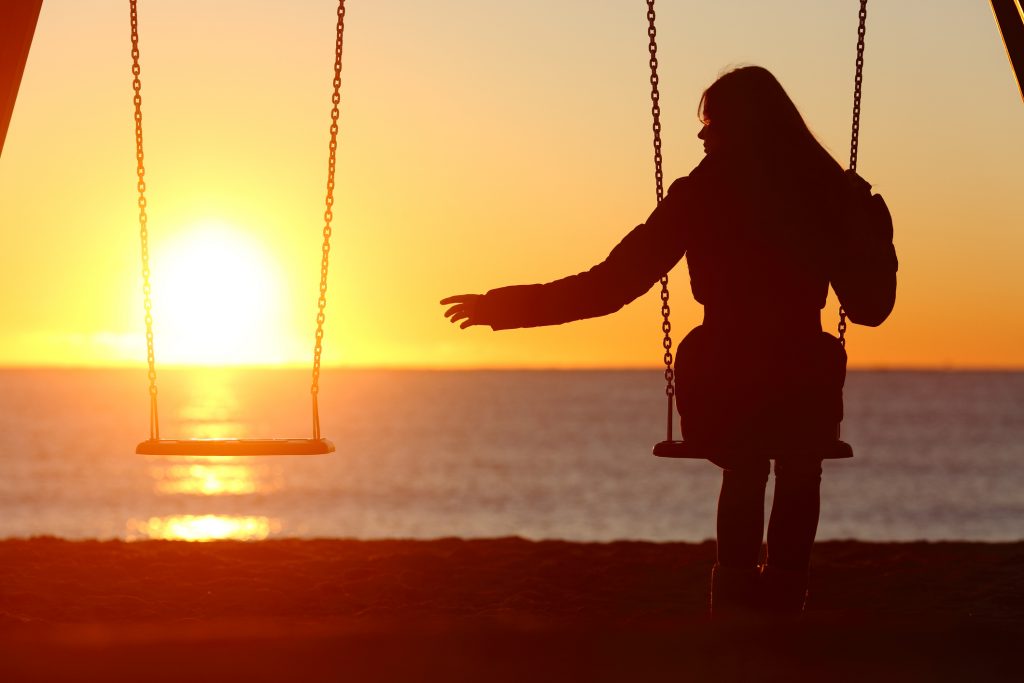 Woman sitting by an empty swing