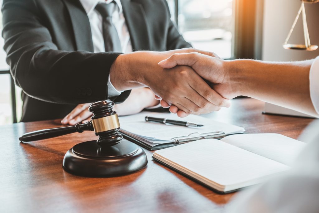 People shaking hands over desk with gavel in foreground