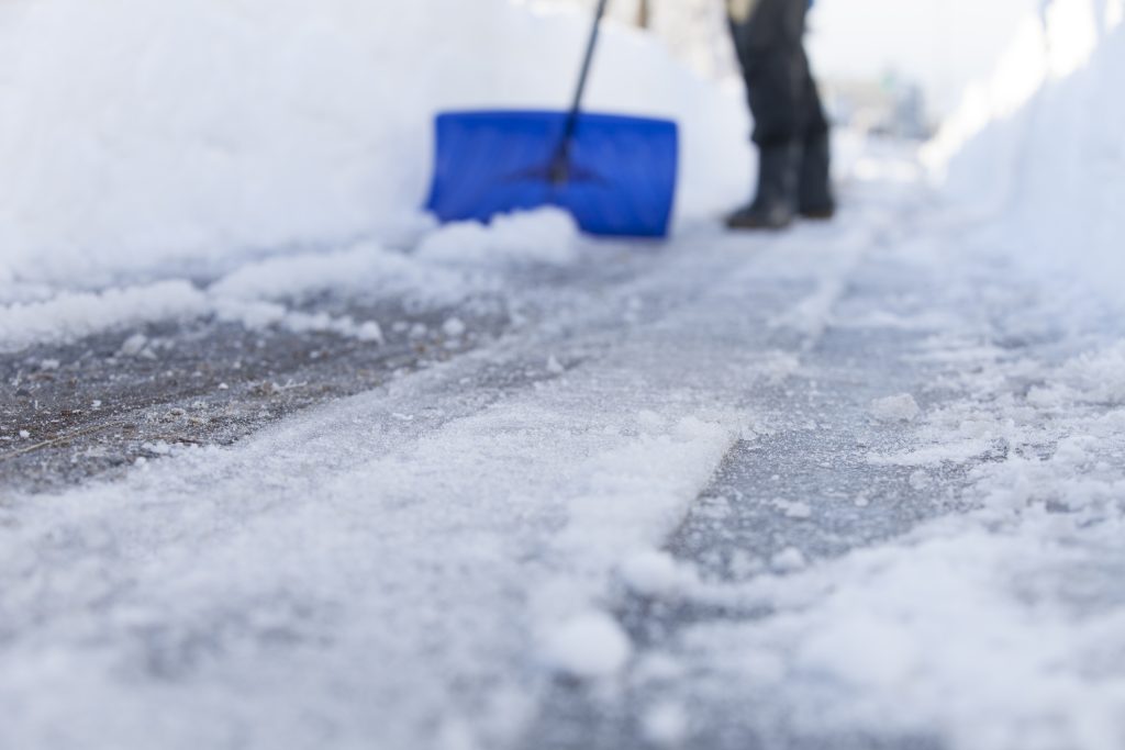 Person shoveling snow on a sidewalk