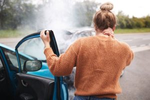 Woman rubbing neck because she just got into a car accident. 