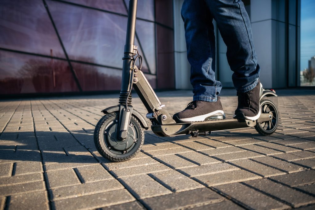 Close up view of a person's legs riding a rental scooter
