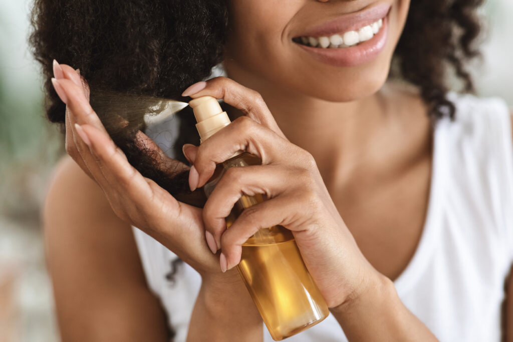 Black woman spraying hair care products into her hair