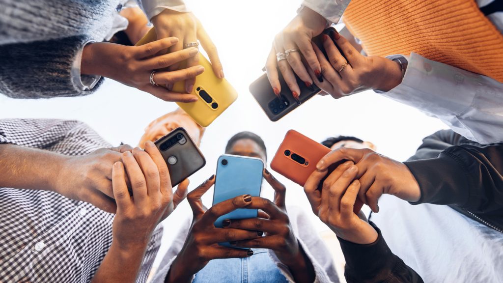 People standing in a circle looking at their smartphones