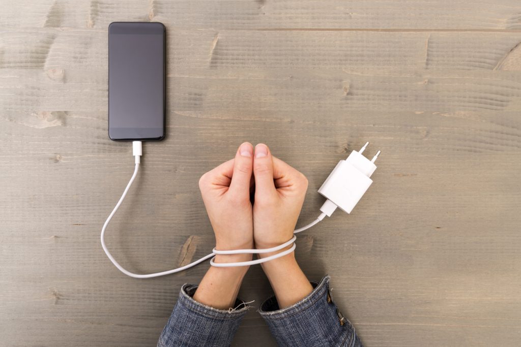 A person's hands tied with a smartphone charging cable