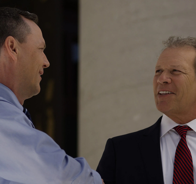 GarywClient 1 Two men in business attire shaking hands and talking outdoors