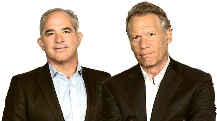 Two men in suits posing side by side, one smiling and one with arms crossed